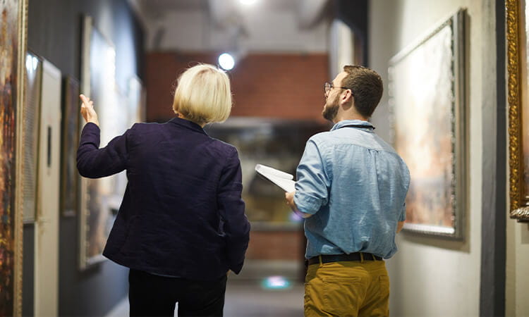 Two people walking through an art gallery. 