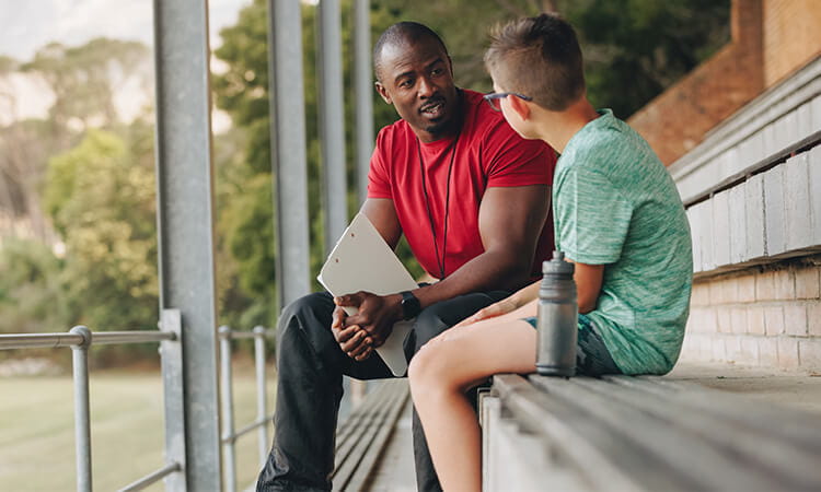 Man talking to boy in an outdoor counselling session.